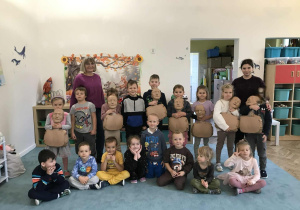 Dzieci i nauczycielka pozują do wspólnego zdjęcia w sali przedszkolnej. Dzieci trzymają fantomy do ćwiczeń RKO. Zdjęcie częściowo anonimizowane.