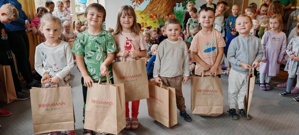 Dzieci, które otrzymały w konkursie nagrody pozują do wspólnego zdjęcia. W tle pozostałe dzieci z przedszkola. Ujęcie 2