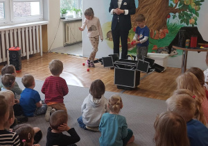 Iluzjonista w trakcie występu. Ujęcie 3. Artyście towarzyszy dwoje dzieci.