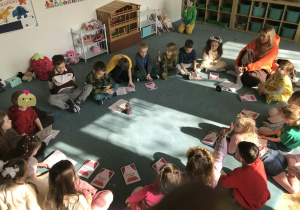 Dzieci i nauczycielka siedzą na dywanie. Grupa 5. Ujęcie 2