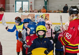 Zwycięska drużyna w czasie zmagań sportowych. Dzieci stoją w łyżwach i czekają na sygnał do startu kolejnej konkurencji.