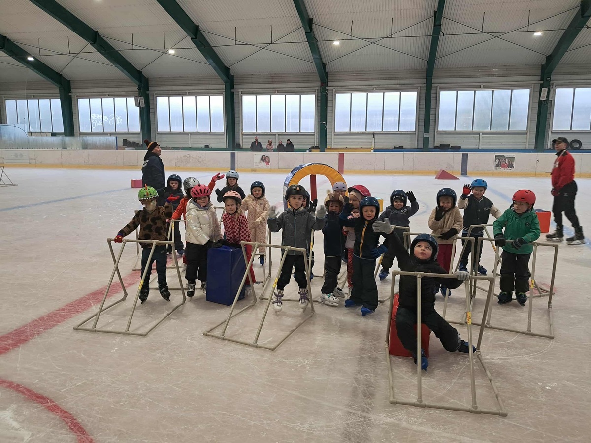 Dzieci pozują do wspólnego zdjęcia w czasie zajęć na lodowisku.