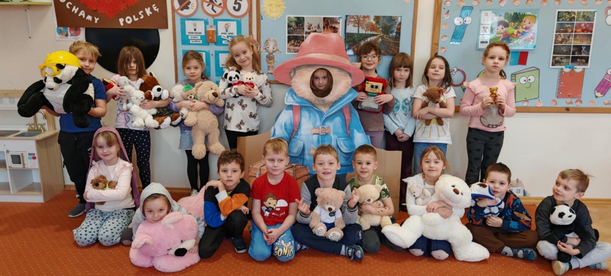 Dzieci pozują do wspólnego zdjęcia i prezentują swoje ulubione przytulanki - misie pluszowe.