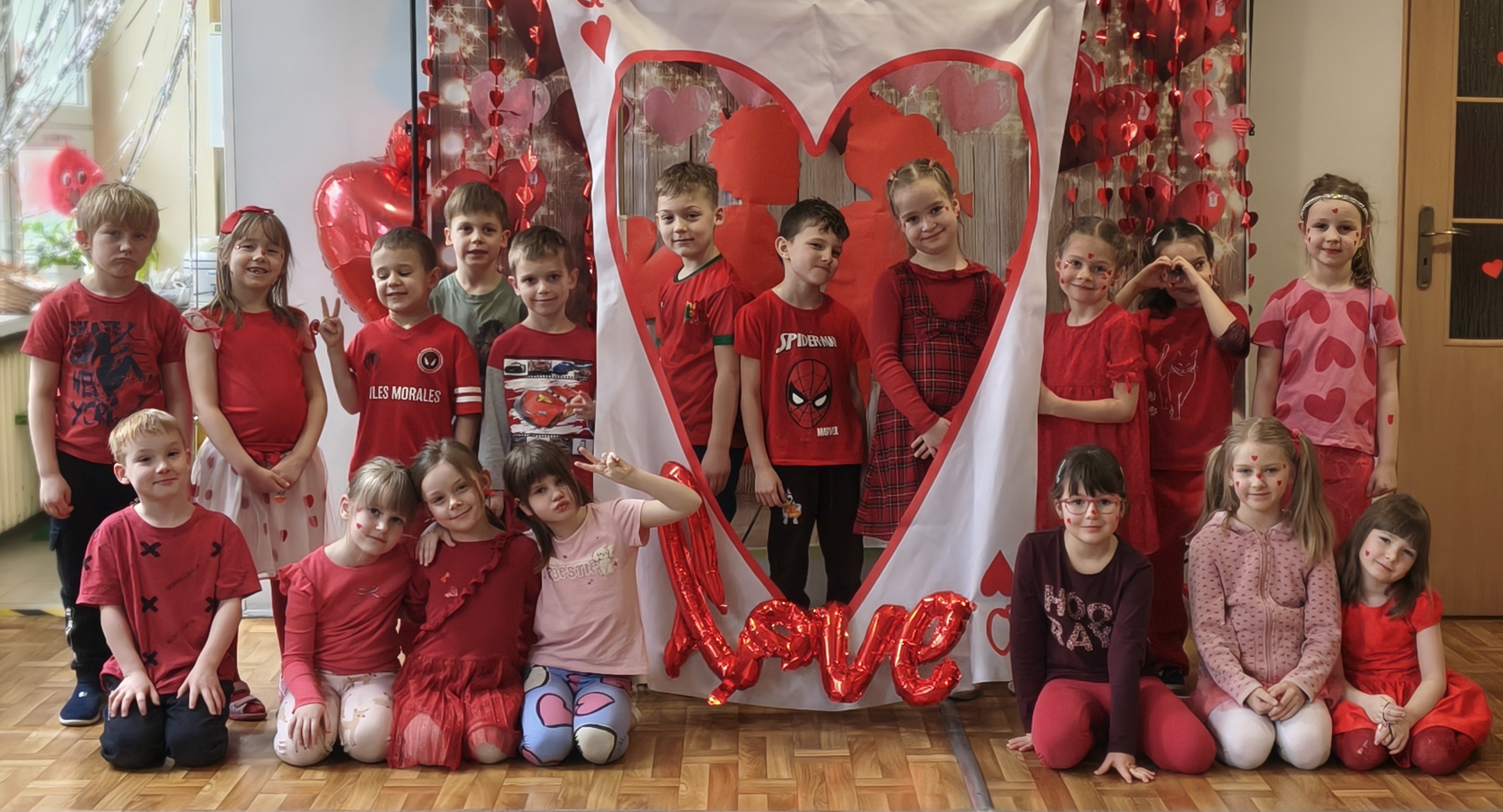 Dzieci pozują do wspólnego zdjęcia na tle walentynkowych dekoracji.