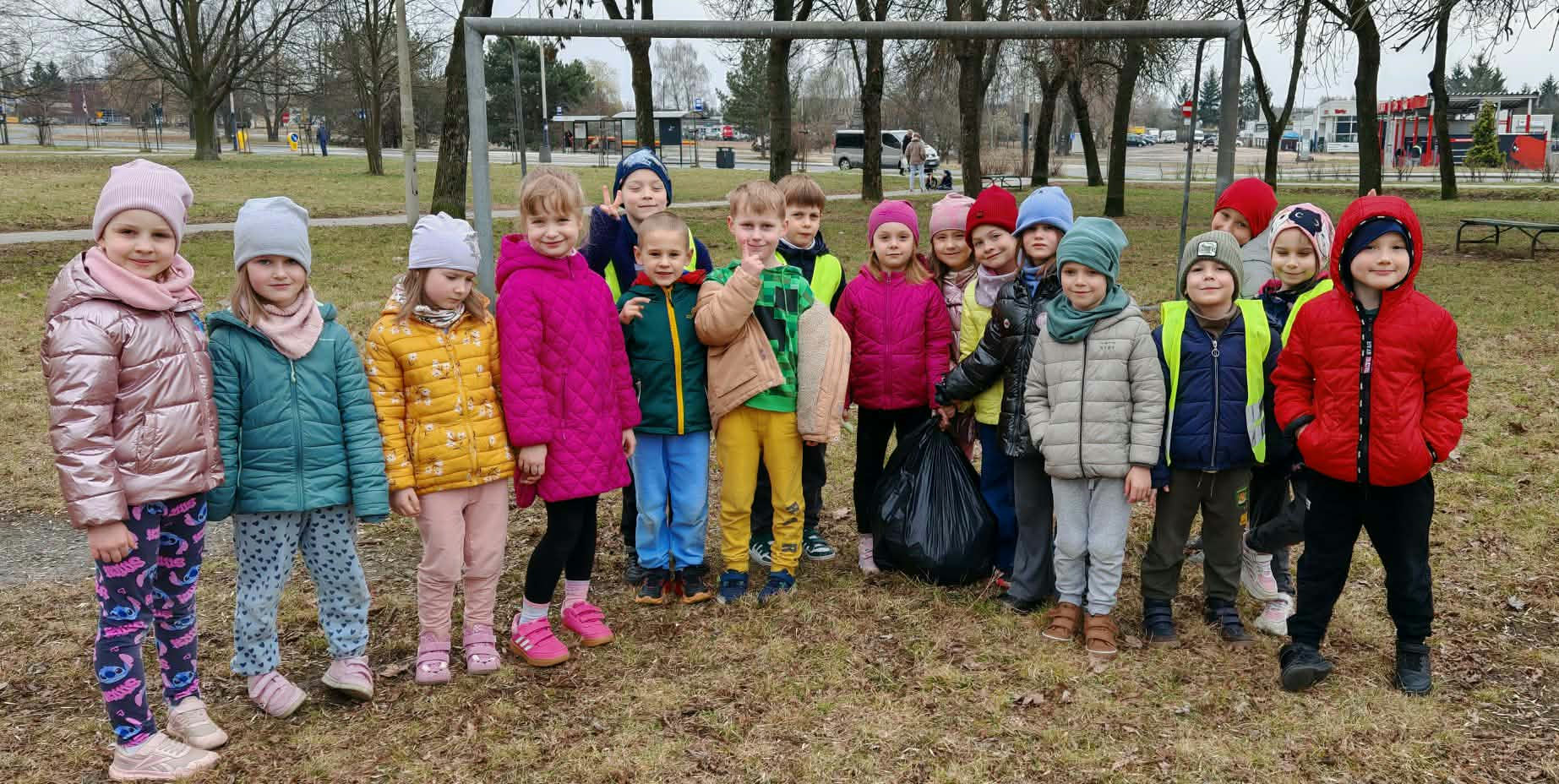Dzieci z grupy 4 pozują do wsp&oacute;lnego zdjęcia w czasie wiosennych porządk&oacute;w w okolicy przedszkola.