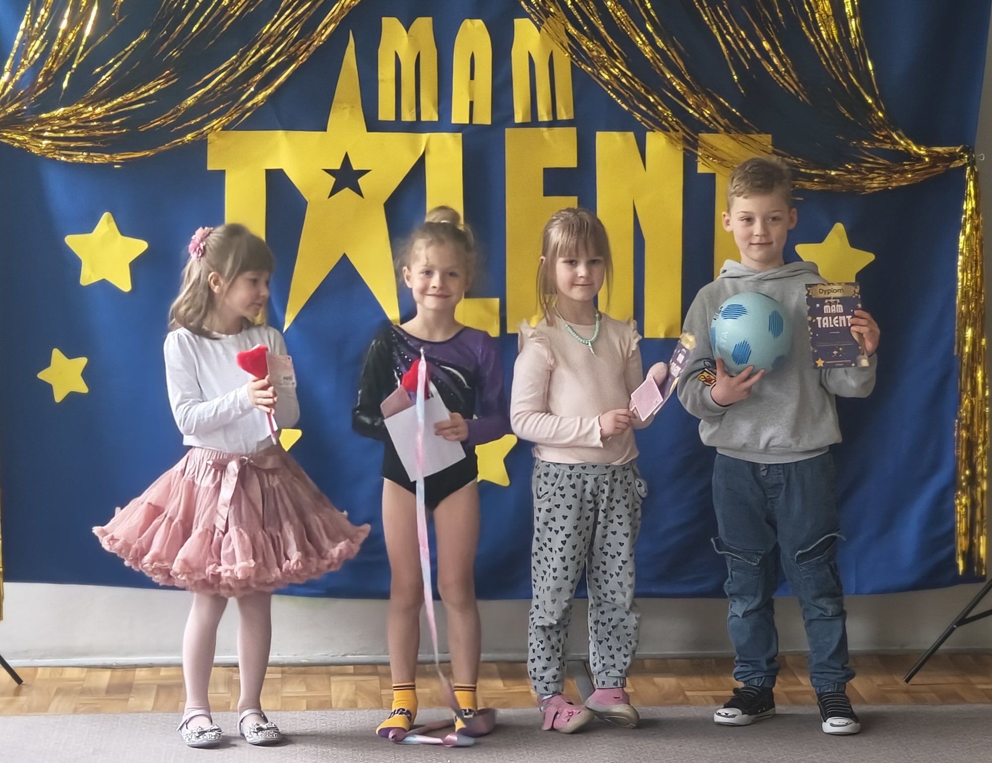 Dzieci z grupy 4 pozują do zdjęcia po występie. Zaprezentowały: pokaz gimnastyki artystycznej i wiersz, grę na flecie, akrobacje z piłką, piosenkę.