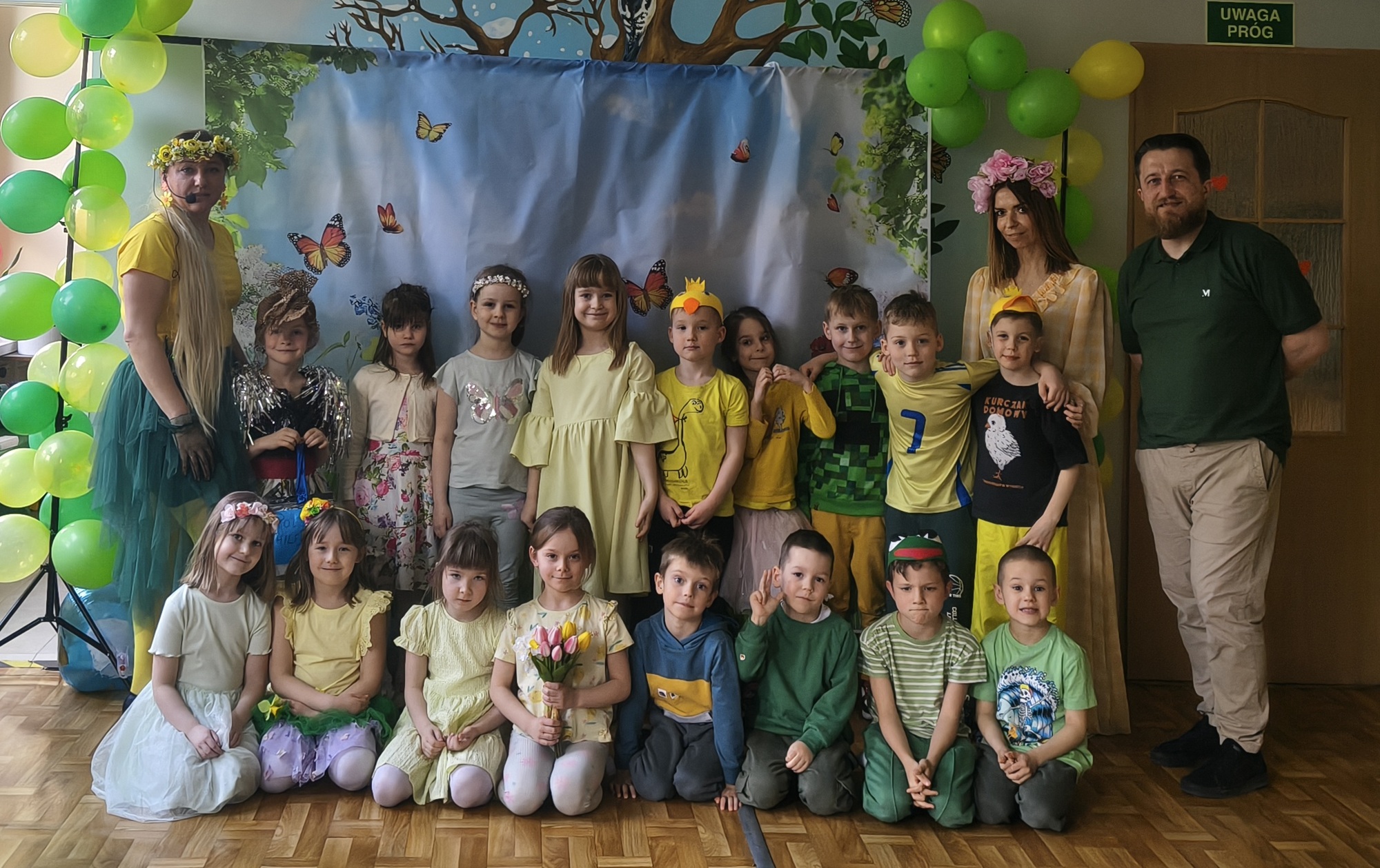 Dzieci i nauczyciele z grupy 4 pozują do wsp&oacute;lnego zdjęcia na balu wiosny.