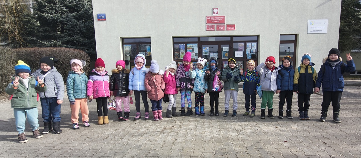 Grupa dzieci pozuje do wsp&oacute;lnego zdjęcia na tle SP44.