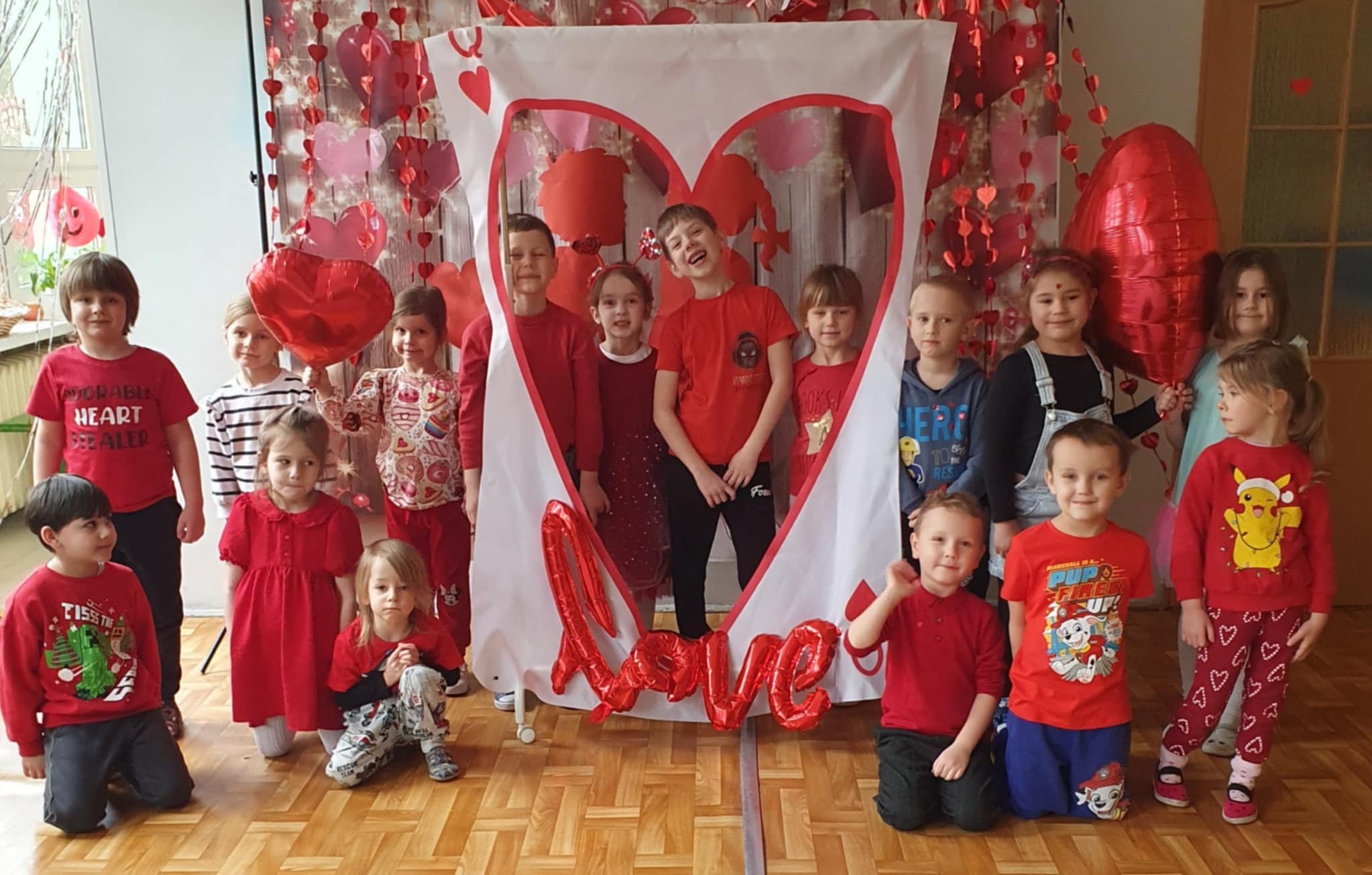 Dzieci pozują do wspólnego zdjęcia w otoczeniu walentynkowych ozdób.