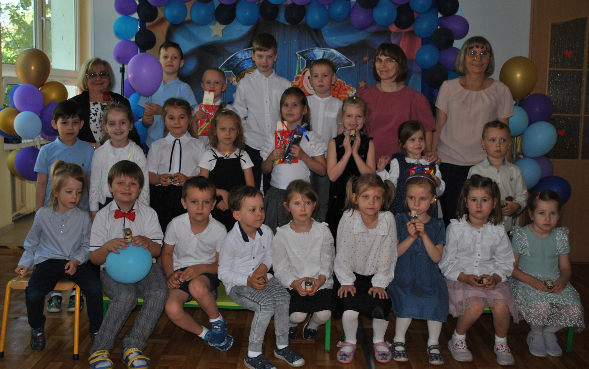 Dzieci, dyrektor i nauczycielki pozują do wsp&oacute;lnego zdjęcia.
