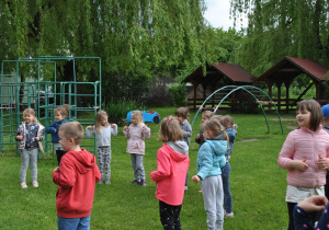 Dzieci tańczą w ogrodzie.