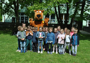 Grupa dzieci pozuje do wspólnego zdjęcia z dużą maskotką Scooby-Doo.