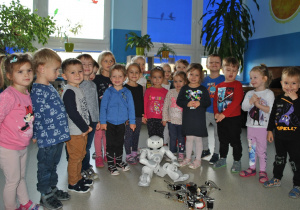 Grupa dzieci pozuje do zdjęcia z robotami. Ujęcie 1