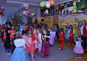 Dzieci w przebraniach wspólnie tańczą na balu.