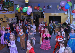 Dzieci w przebraniach wspólnie tańczą na balu.