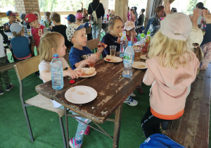 Dzieci przy stolikach w trakcie posiłku. Ujęcie 1.