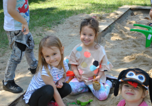 Dzieci podczas zabawy w piaskownicy. Zbliżenie na trzy dziewczynki.