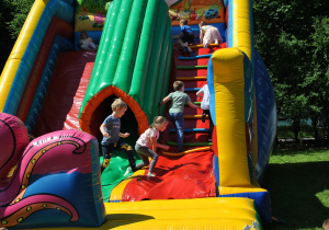 Dzieci podczas zabawy na zjeżdżalniach dmuchanego zamku.