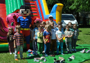 Dzieci z grupy 5 pozują do wspólnego zdjęcia z maskotką - supermenem i nauczycielką.