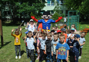 Dzieci z grupy 2 pozują do wspólnego zdjęcia z maskotką - supermenem i nauczycielką.