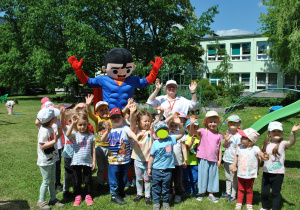 Dzieci z grupy 1 pozują do wspólnego zdjęcia z maskotką - supermenem i nauczycielką.