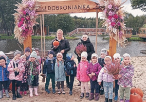 Grupa dzieci razem z nauczycielkami pozuje do wspólnego zdjęcia, na tle bramki z napisem "Dobronianka".