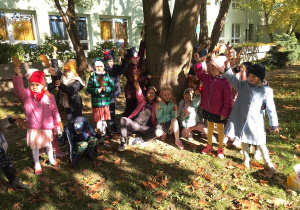Dzieci pozują do zdjęcia przy drzewie.