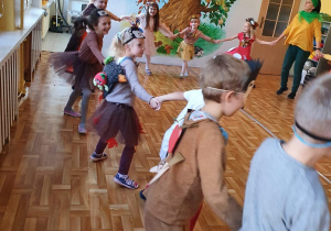 Dzieci na balu tańczą w kółeczku z nauczycielką.