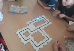 Dzieci przy stoliku bawią się robotami edukacyjnymi.