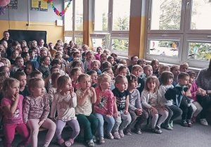 Widok ze sceny na widownię pełną dzieci. Między dziećmi widać nauczycieli.