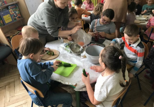 Dzieci i rodzice przygotowują różne sałatki.