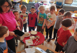 Dzieci i nauczycielka przygotowują się do wypieku chleba.