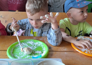 Dzieci zagniatają ciasto chlebowe.