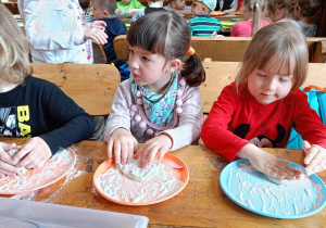 Dzieci zagniatają ciasto chlebowe.