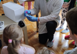 Dzieci z zaciekawieniem oglądają eksperymenty chemiczne.