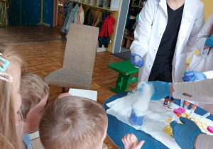 Dzieci z zaciekawieniem oglądają eksperymenty chemiczne.