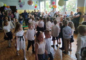 Dzieci tańczą poloneza. Ujęcie z boku sali.