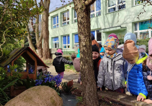 Dzieci szukają śladów wiosny w ogrodzie przedszkolnym.