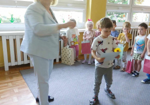 Dzieci odbierają dyplomy i nagrody z rąk dyrektora przedszkola.