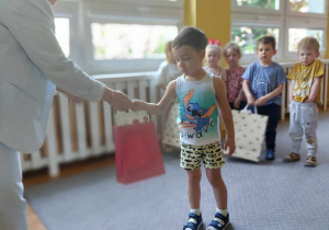 Dzieci odbierają dyplomy i nagrody z rąk dyrektora przedszkola.