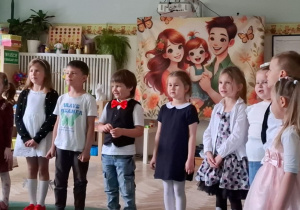 Grupa dzieci stoi podczas występu w sali przedszkolnej. Ujęcie 1
