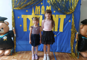 Dwoje dzieci pozuje do wspólnego zdjęcia na tle napisu "Mam talent".