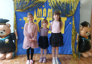 Troje dzieci pozuje do wspólnego zdjęcia na tle napisu "Mam talent".