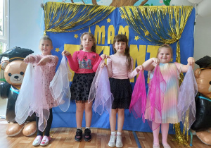 Czworo dzieci pozuje do wspólnego zdjęcia na tle napisu "Mam talent". Dzieci trzymają w wyciągniętych rękach kolorowe chusteczki.