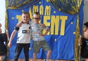 Dwoje dzieci pozuje do wspólnego zdjęcia na tle napisu "Mam talent".