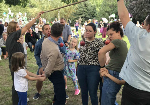 Czworo rodziców bierze udział w konkursie na zjedzenie jabłka zawieszonego na sznurku. Ujęcie 2