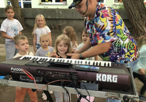 Dzieci zaciekawione oglądają konsolę animatora.