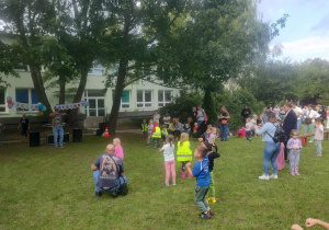 Dzieci, rodzice i nauczycielki wspólnie tańczą do instrukcji animatora. Ujęcie 2