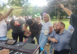 Czworo rodziców bierze udział w konkursie na zjedzenie jabłka zawieszonego na sznurku.
