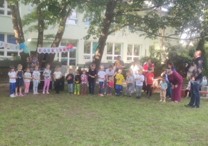 Dzieci w towarzystwie rodziców i animatora przygotowują się do konkursu zręcznościowego.